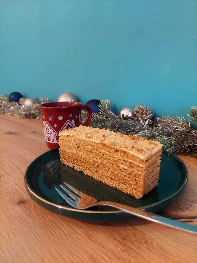 Ein Stück Honigtorte vor der türkisen Wand, winterlich dekoriert