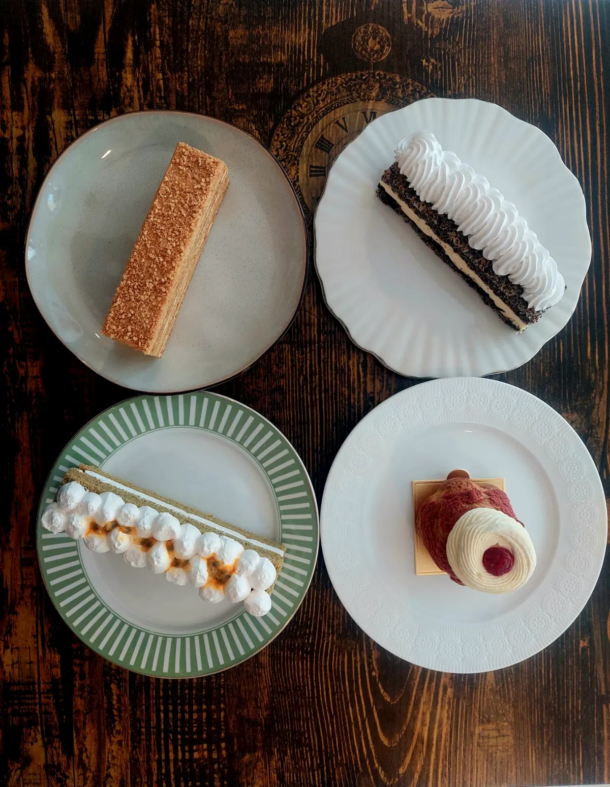 Vier Kuchenstücke auf verschiedenen Tellern, von oben fotografiert