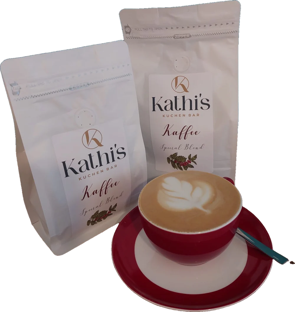 Zwei Tüten Kathi's Kaffee Special Blend, davor ein Cappuccino mit Latte Art